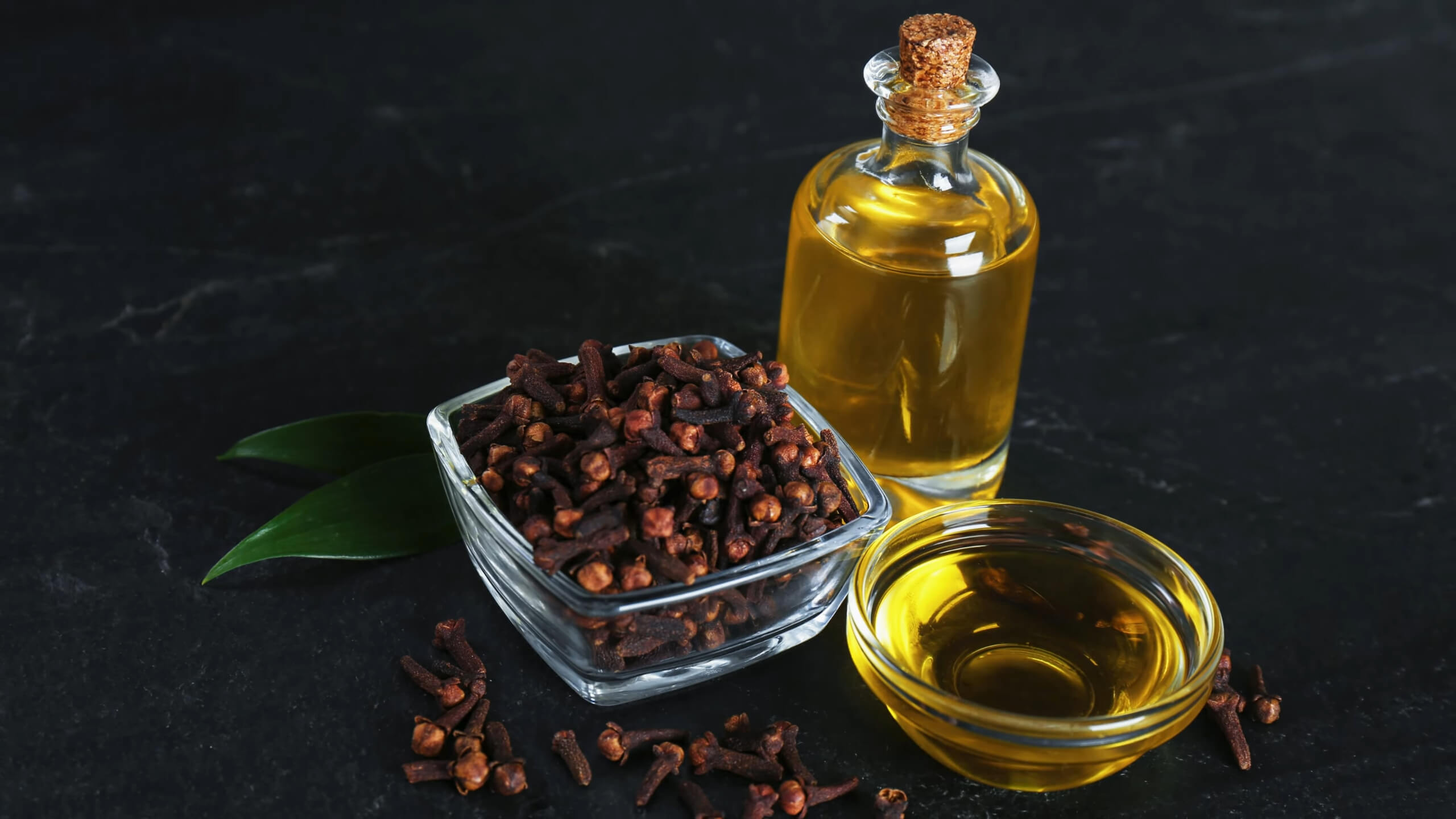 A bowl of cloves and a bottle of clove oil as a natural remedy for a tooth abscess