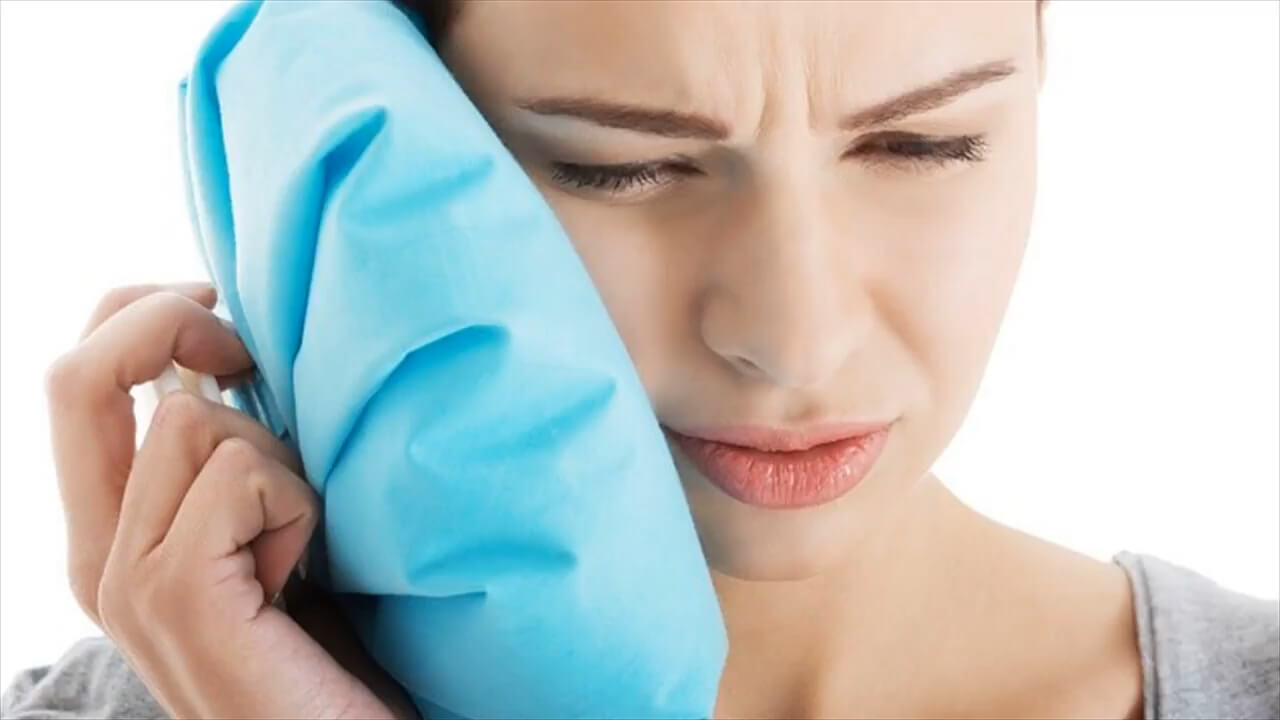 A girl holding a cold compress on her cheek due to a tooth abscess