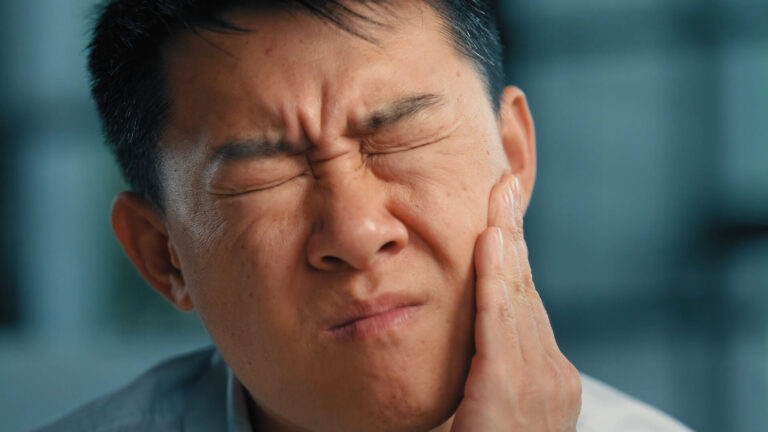 A man holding his cheek due to a toothache