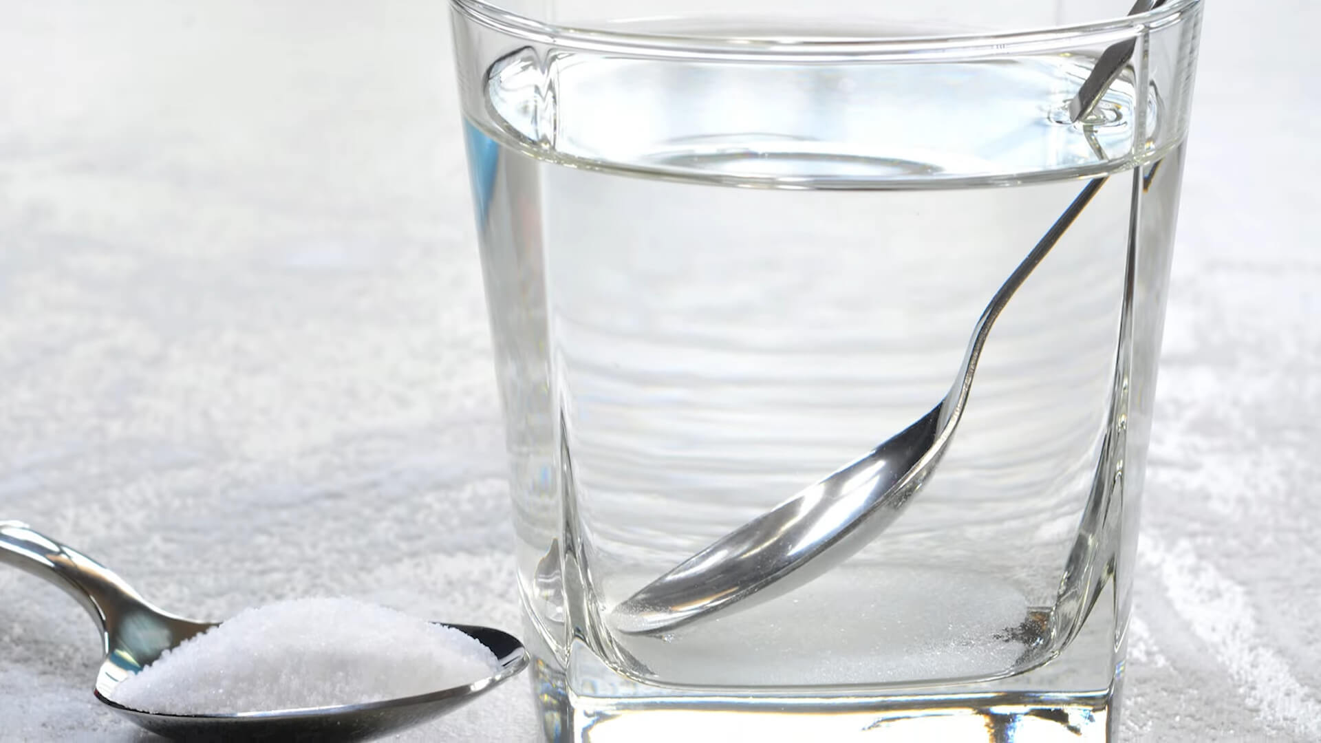 A glass of water with a teaspoon of kitchen salt