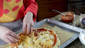 Adding pizza sauce, cheese, and toppings