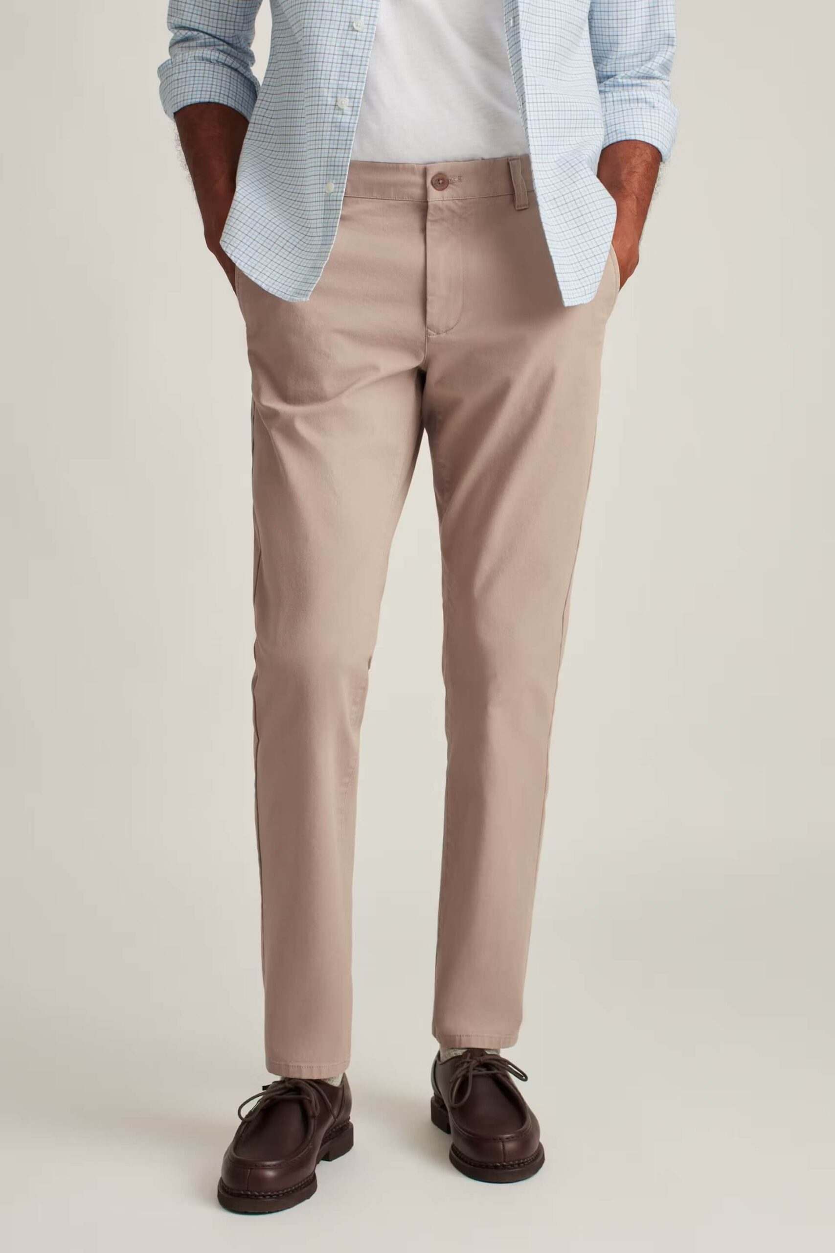 Man wearing light brown stretch washed chinos paired with a white t-shirt and brown leather shoes