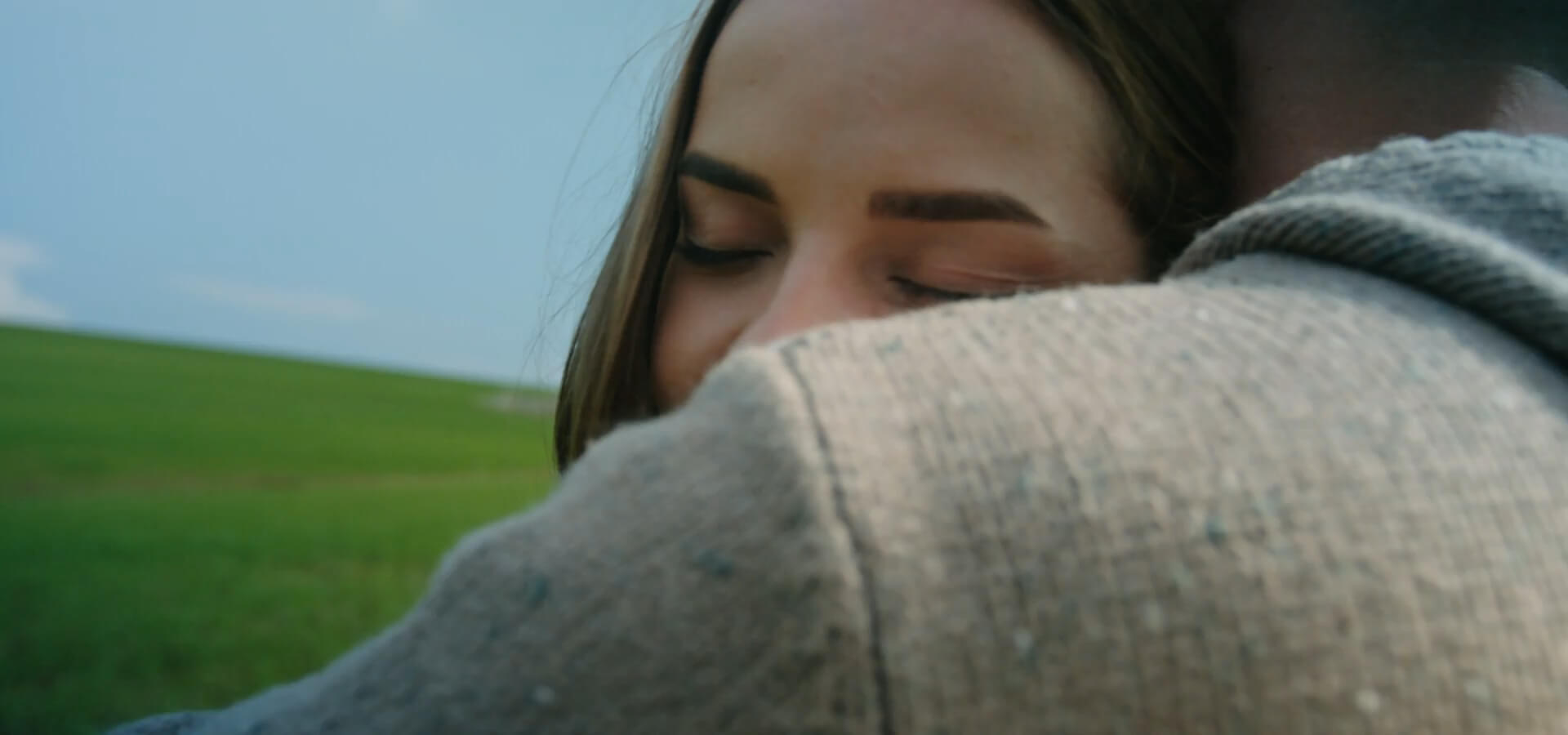 A woman peacefully resting her head on partner’s shoulder