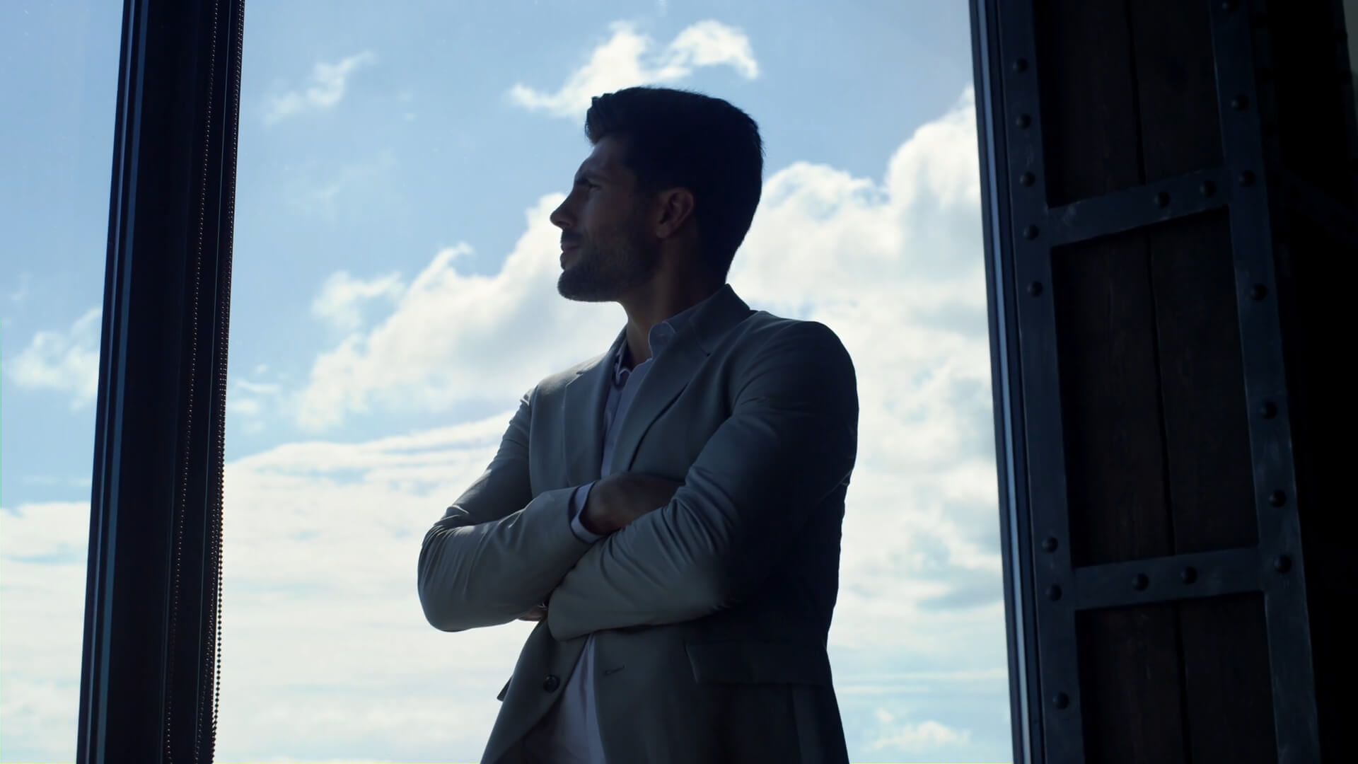 A man standing by a window with arms crossed