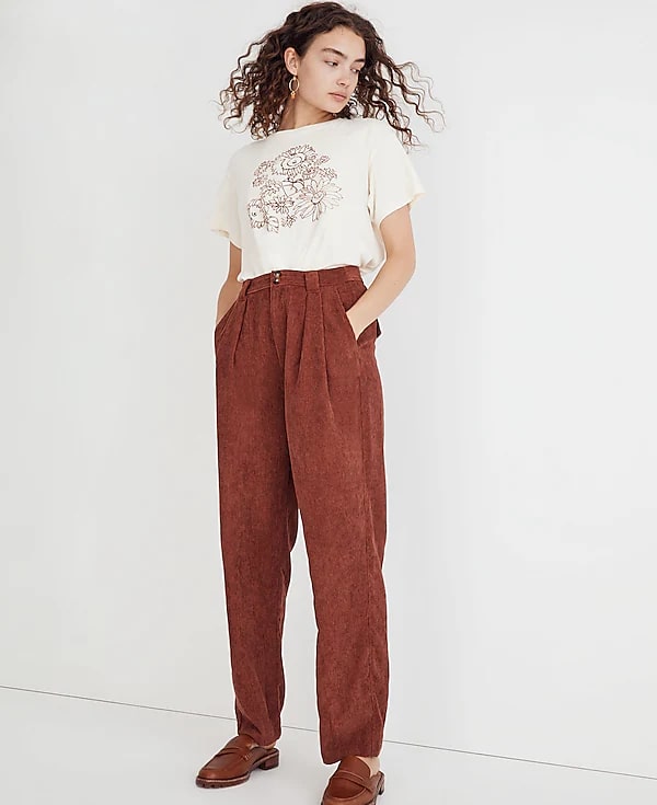 Model in a cream floral t-shirt paired with high-rise rust-colored corduroy pants