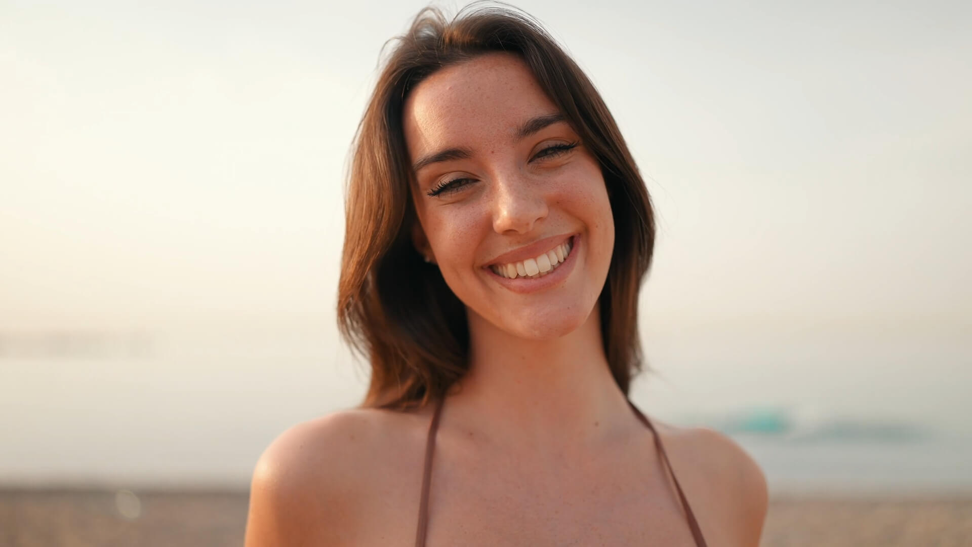 A young woman smiling brightly on a beach