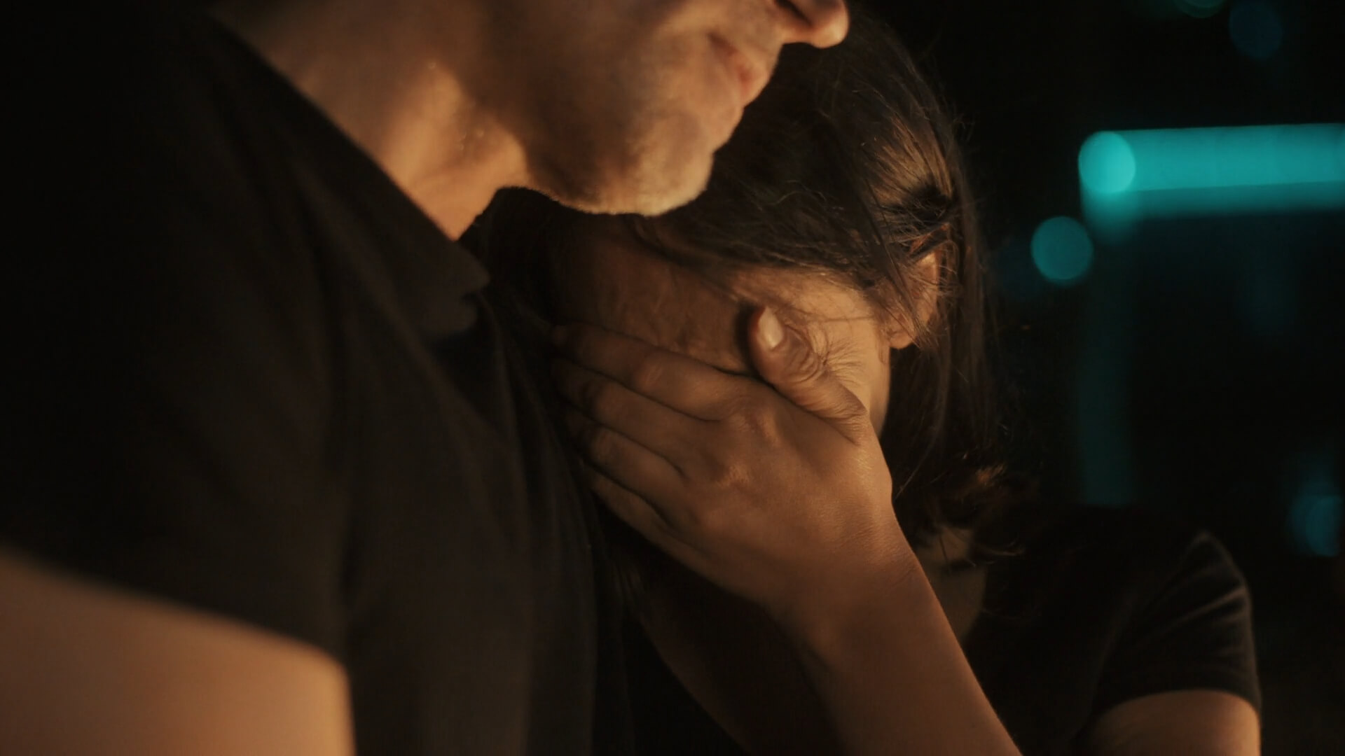 A woman, comforted by a man’s presence, hides her face in his shoulder