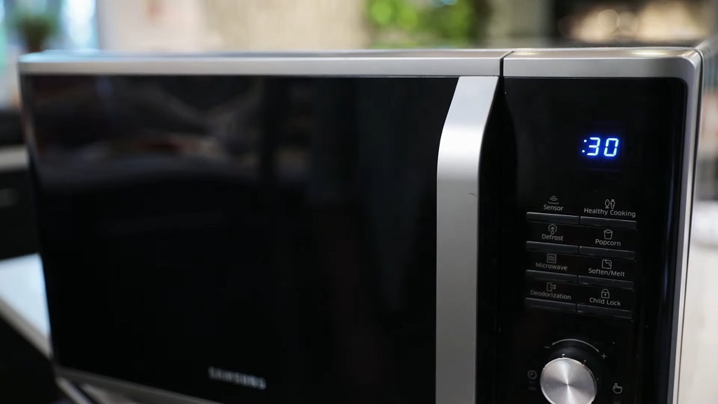 A microwave with a sleek black design displaying a countdown timer