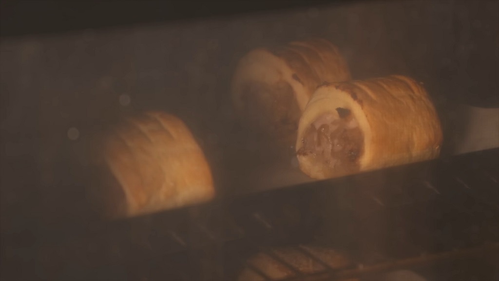 An oven with sausage rolls visible through the glass door