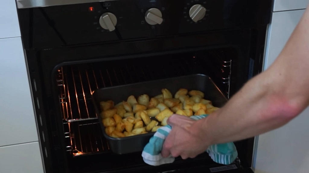 Placing the baking tray with potatoes in the oven