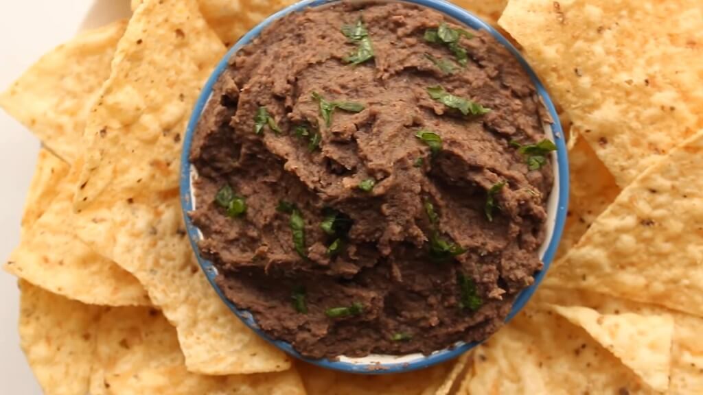 A blue bowl filled with spicy black bean dip