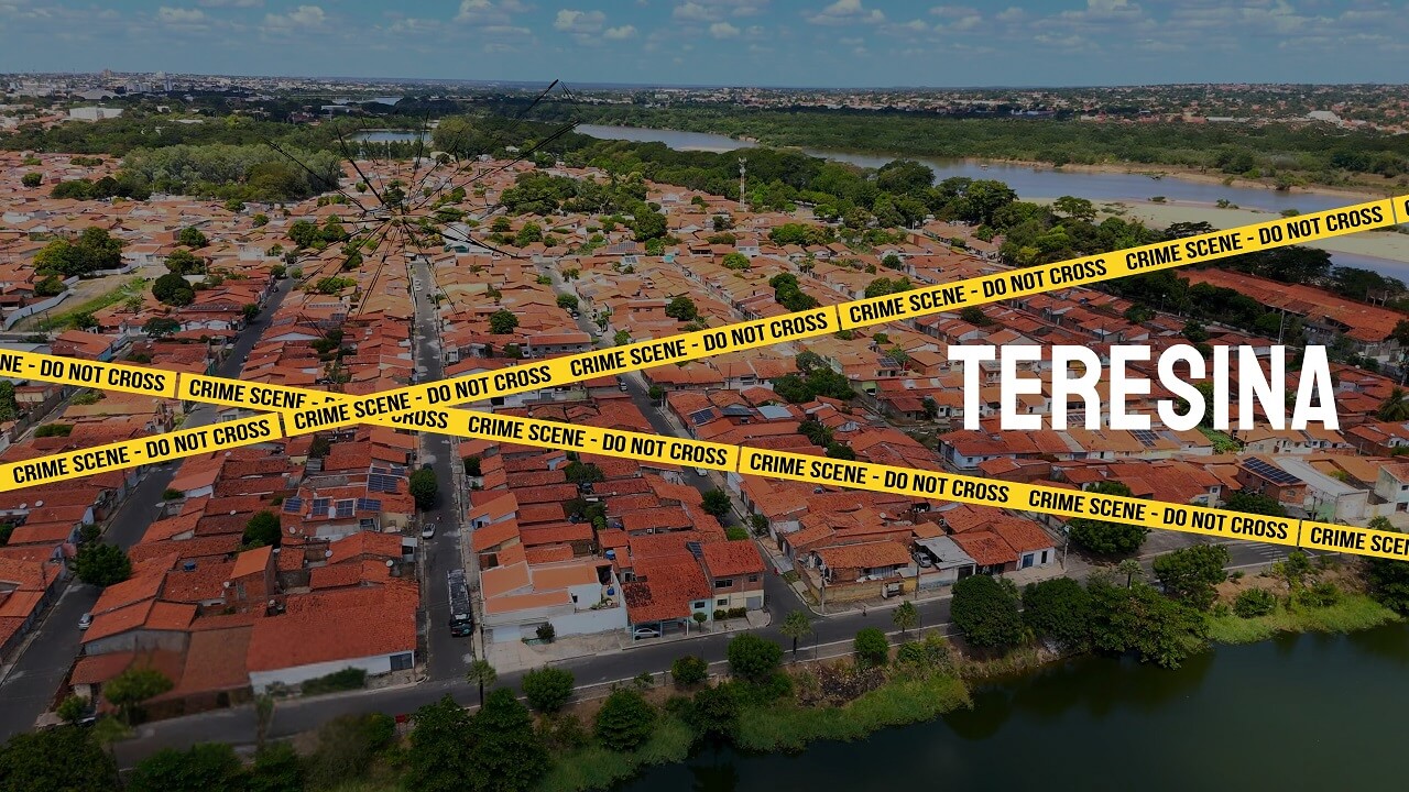 Aerial view of Teresina featuring red-tile-roofed houses, green trees, and a river in the distance