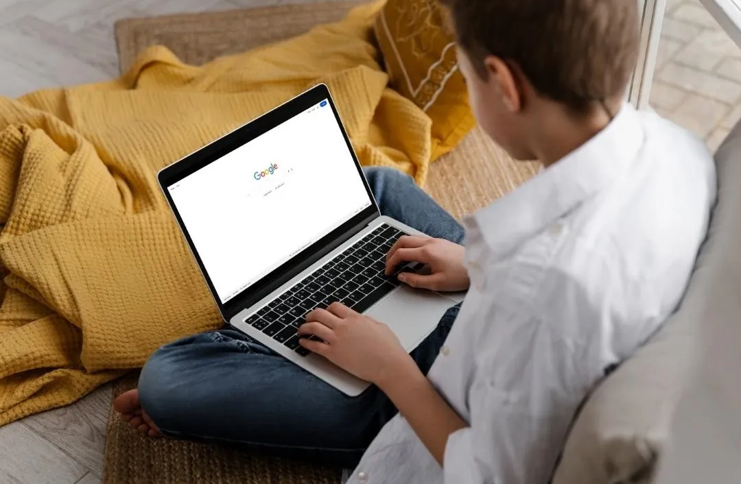 A boy using a laptop to search on Google