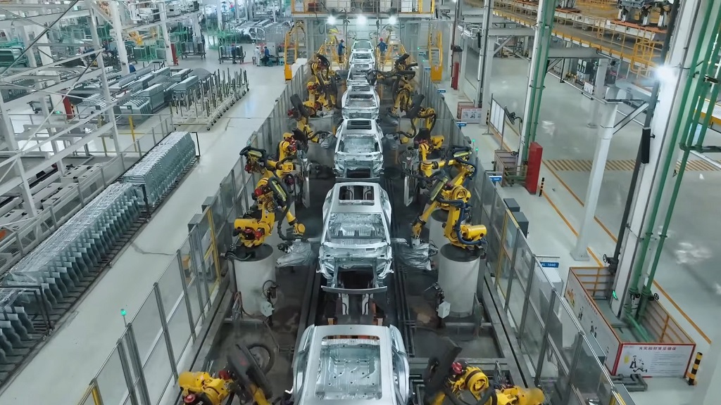 Assembly line inside a BYD`s modern factory, featuring robotic arms assembling car frames