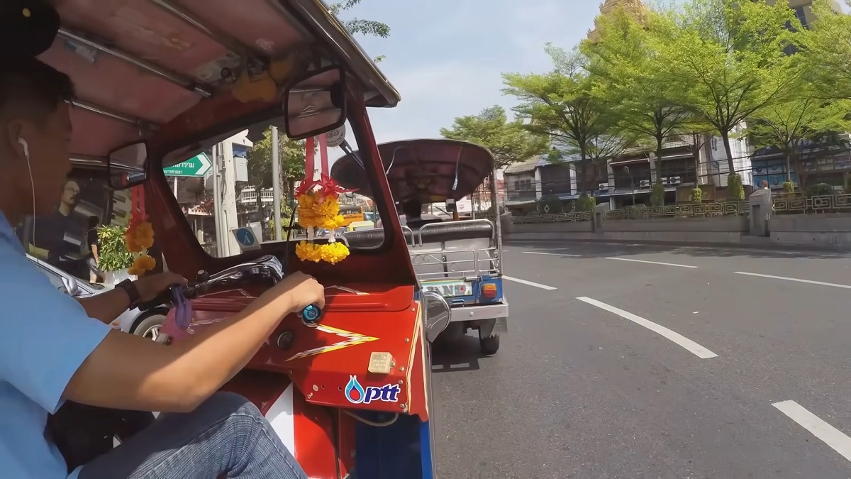 A tuk-tuk driver navigating through the streets of Thailand